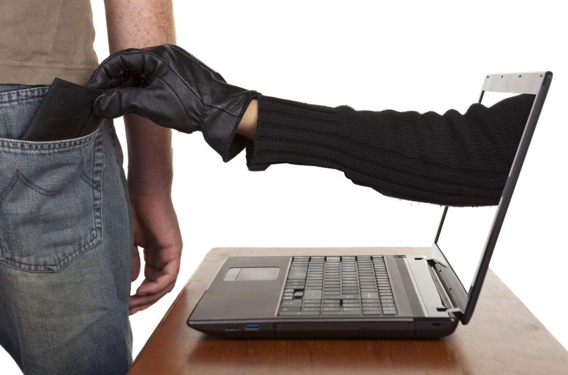 Internet,Theft,-,A,Gloved,Hand,Reaching,Through,A,Laptop